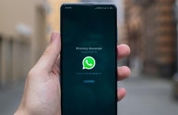 Smartphone against blurred background with WhatsApp logo displayed on the screen; photo credit: Mika Baumeister / Unsplash