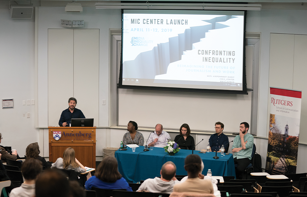 Panel of speakers at the front of a large lecture hall