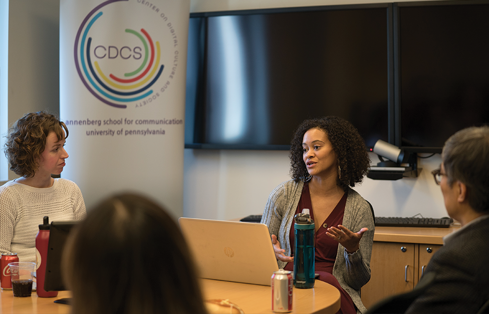 Woman speaking to a group sitting around a table