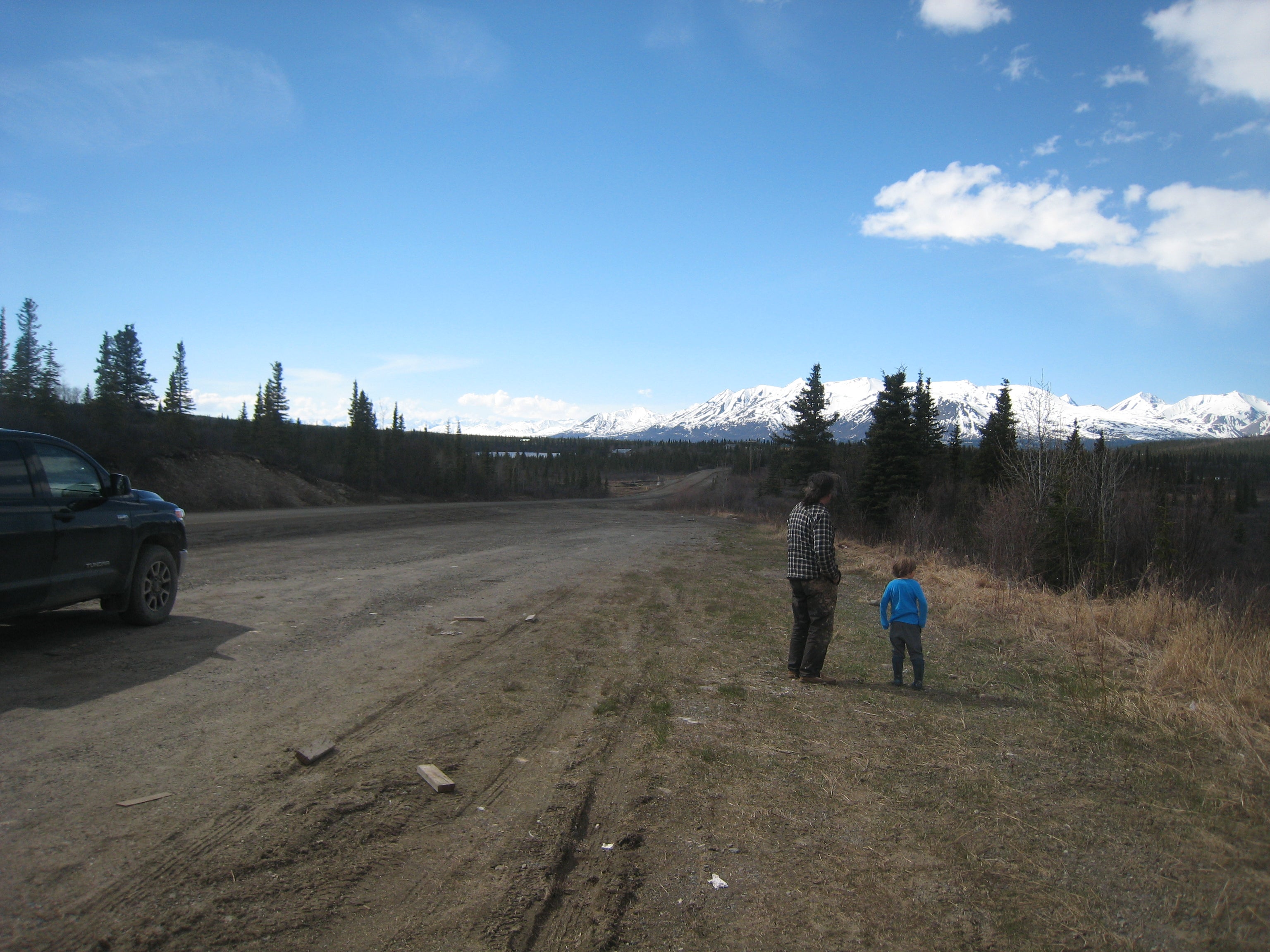 Adult and child standing on the side of a road in Alaskan landscape
