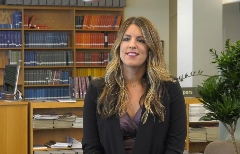 Jennifer Henrichsen seated with shelves of library books behind her