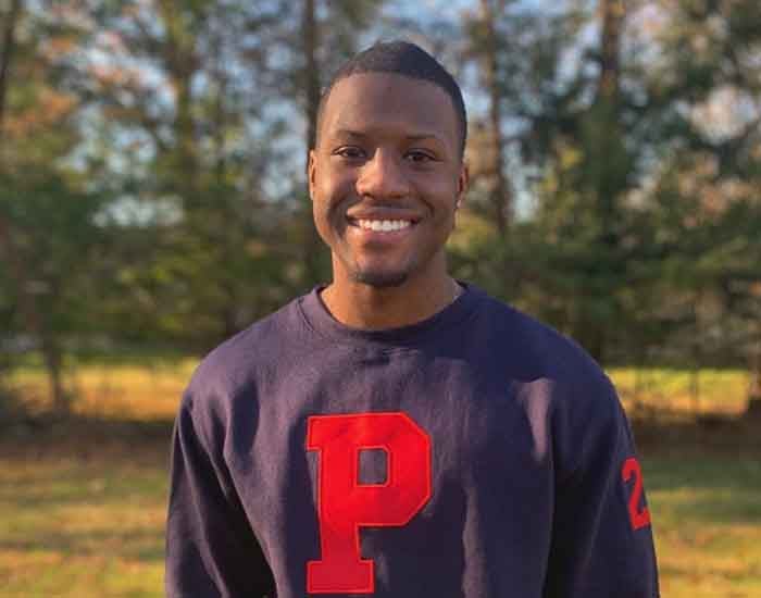 Winston Britton outdoors in a navy sweatshirt with a red P