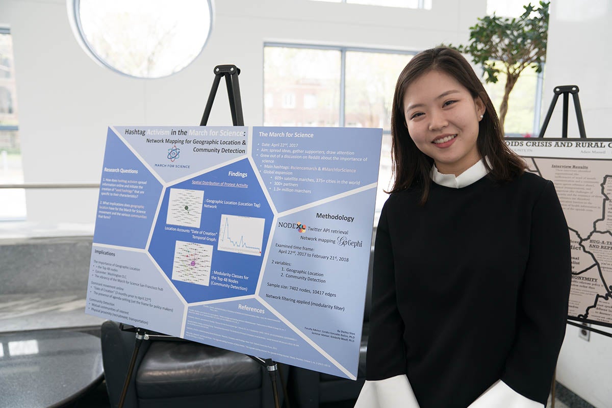 Shelley Shim poses with blue thesis poster.