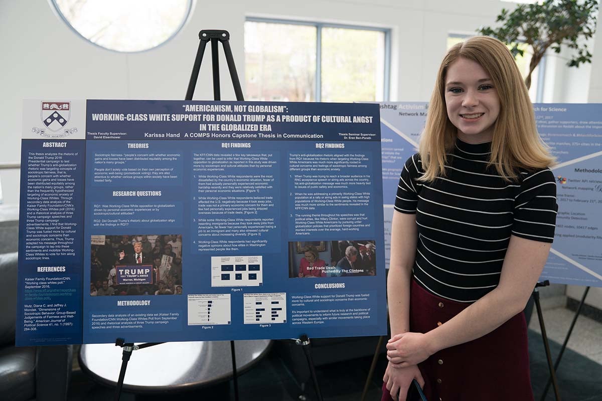 Karissa Hand poses with blue thesis poster.