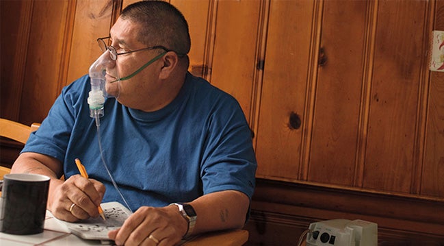 Man on breathing machine performing crossword puzzle