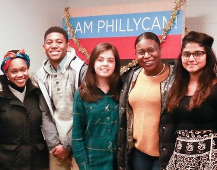 Five students standing together and smiling at the camera