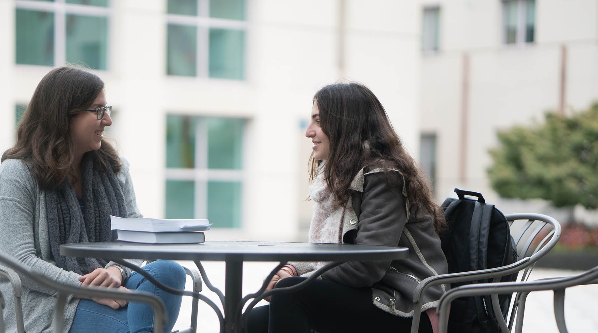 Student sitting at a table with a graduate student TA outside the Annenberg building