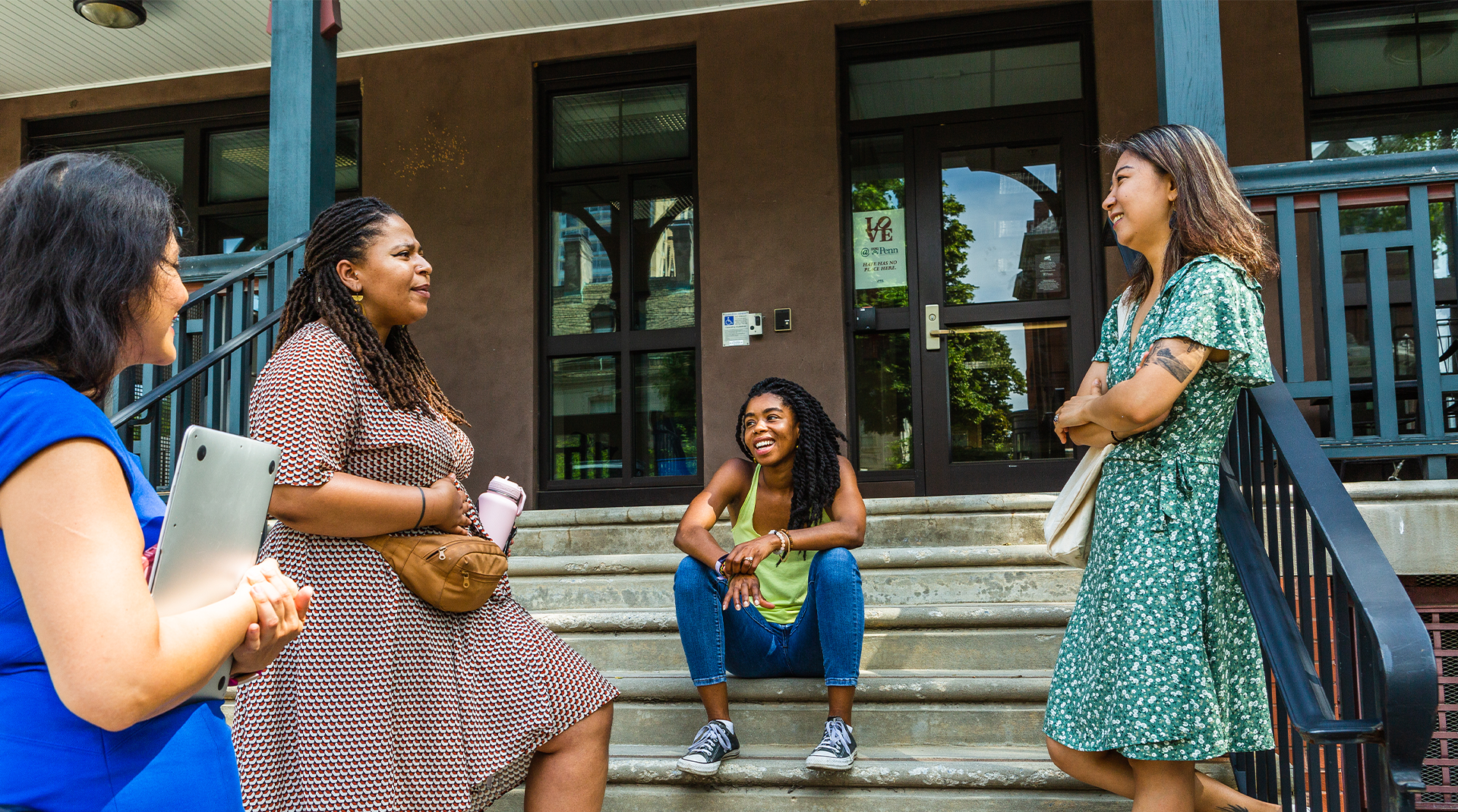 Four women standing on steps and talking to one another