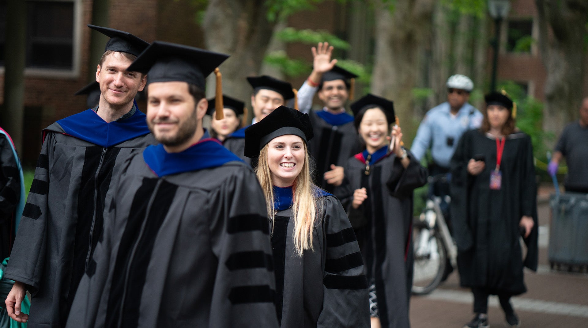 Students in graduation caps and robes walking outdoors and smiling