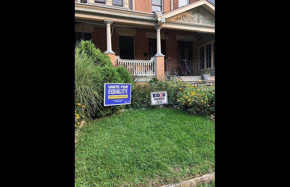 A lawn with grass and flowers and two signs. Neither appears to be handmade. One says “Unite for equality. Vote by November 3rd” with the Human Rights Campaign logo and information on how to sign a petition. Another is a Biden Harris 2020 campaign sign.