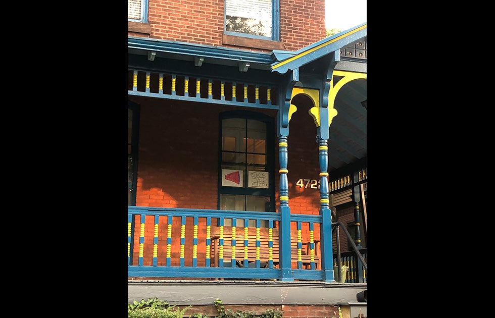 An apartment window with two handmade signs. One is of a red megaphone and another says Black Lives Matter as if it is the message coming from the megaphone.