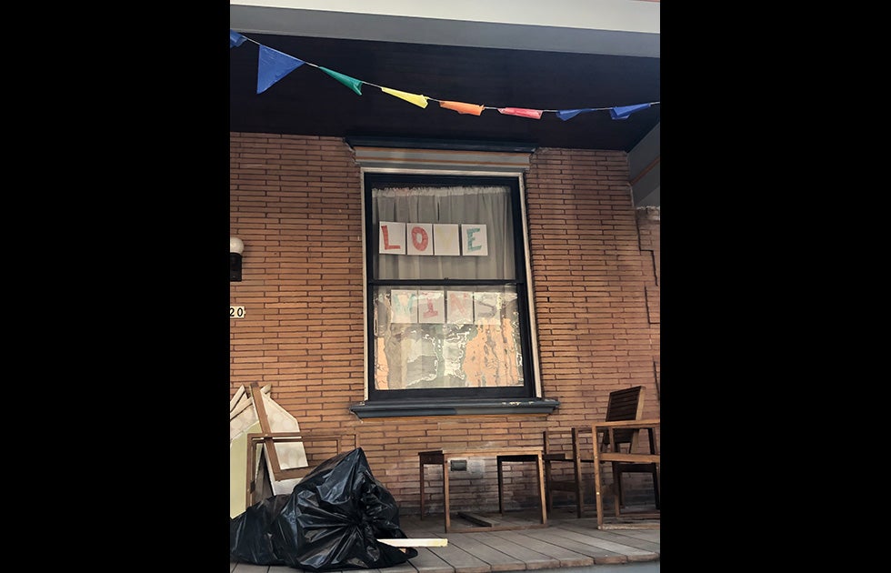 window with the words “LOVE WINS” printed. Each letter is on a separate piece of paper and drawn with a different color marker.