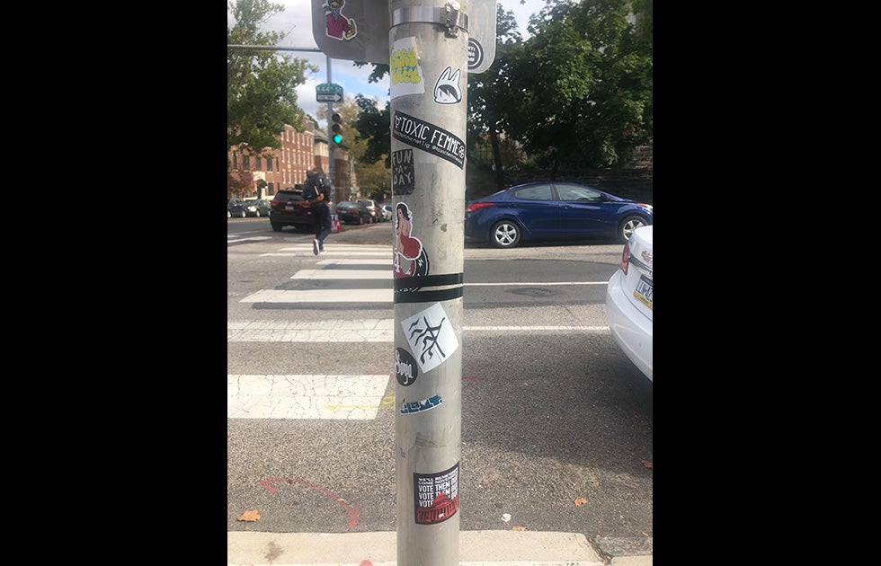 Telephone pole with various stickers, including one that says “Toxic Femme” and another that says “We’ll remember come November vote them out vote them out vote them out” and a picture of the Capitol building.