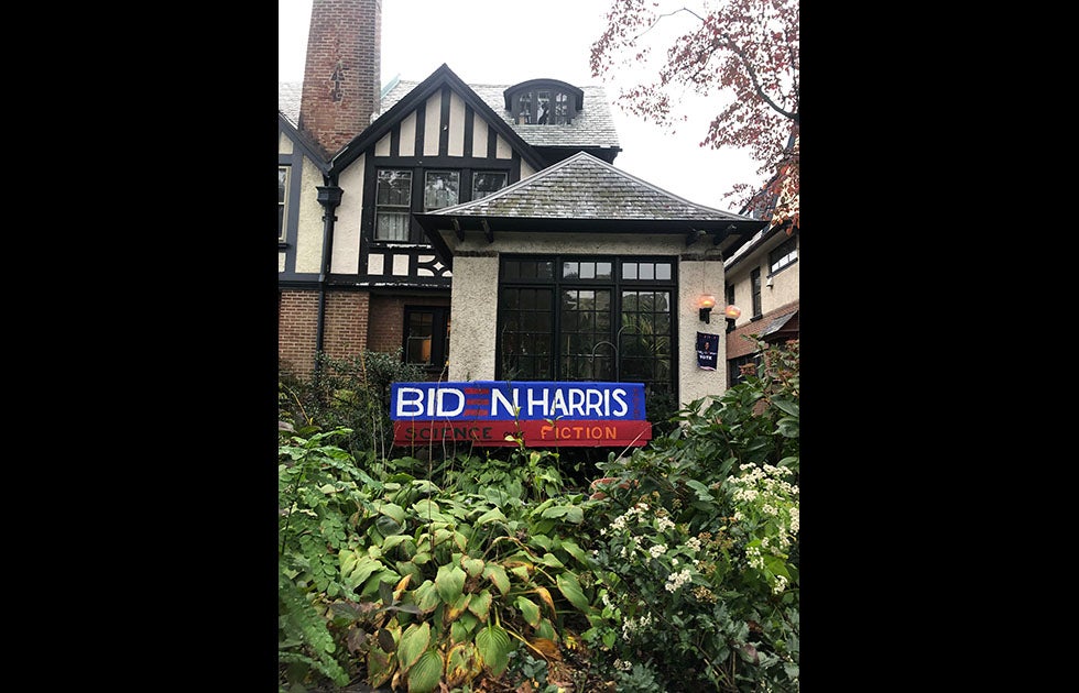 Large handmade banner that says Biden Harris Science over Fiction outside of a house. There is another sign in the background that says “Nasty Women Vote”