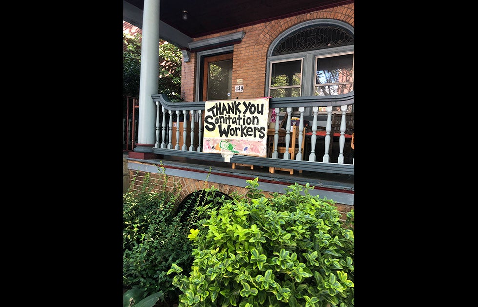 Porch with a hand painted sign that says “Thank you sanitation workers” and an abstract painting of trash.