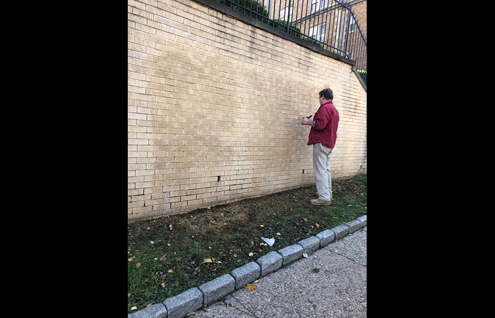White (or white passing) man painting the brick where the RIP Walter graffiti memorial previously stood.