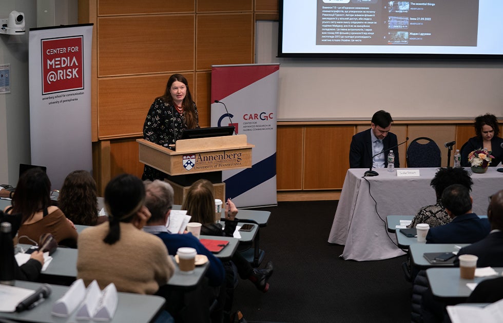A woman speaking at an event in a lecture hall