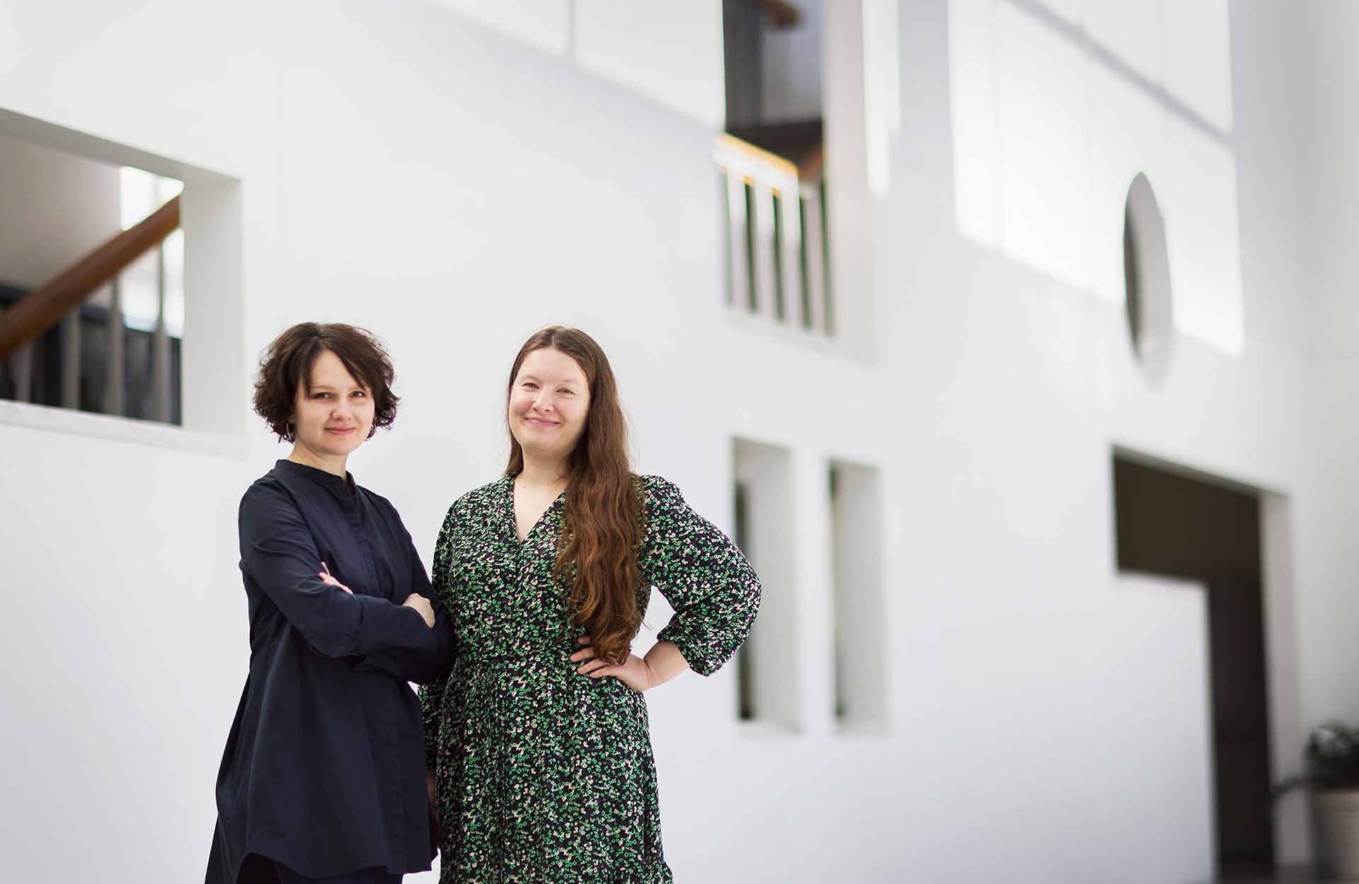 Dariya and Olena 1920 x 1250.jpg Two women posing together in front of a white wall with various architectural cutouts