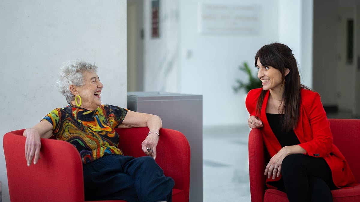 Carolyn Marvin and Sandra Gonzalez-Bailon seated in red chairs talking