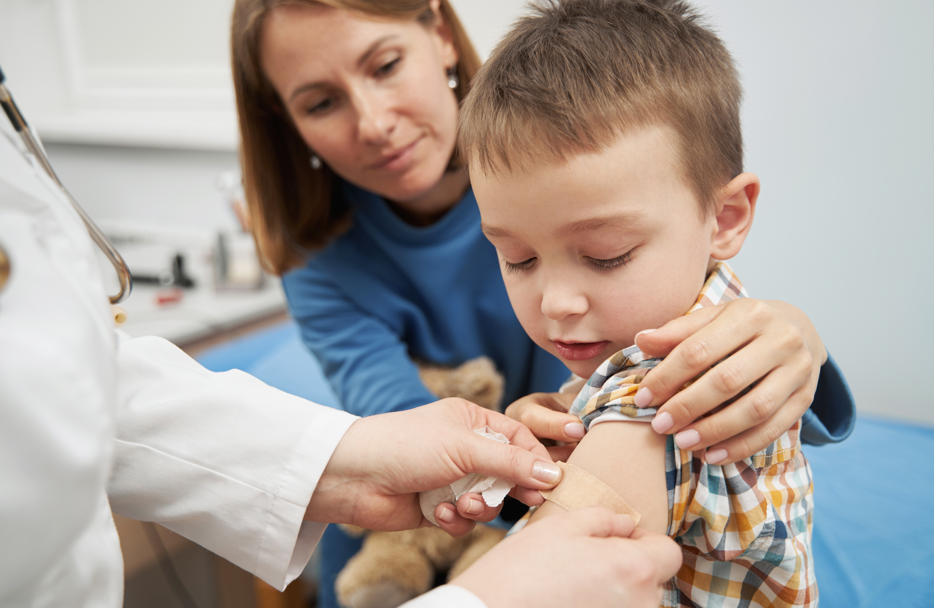 vaccination.png Doctor placing medical bandage a on child's arm after vaccination