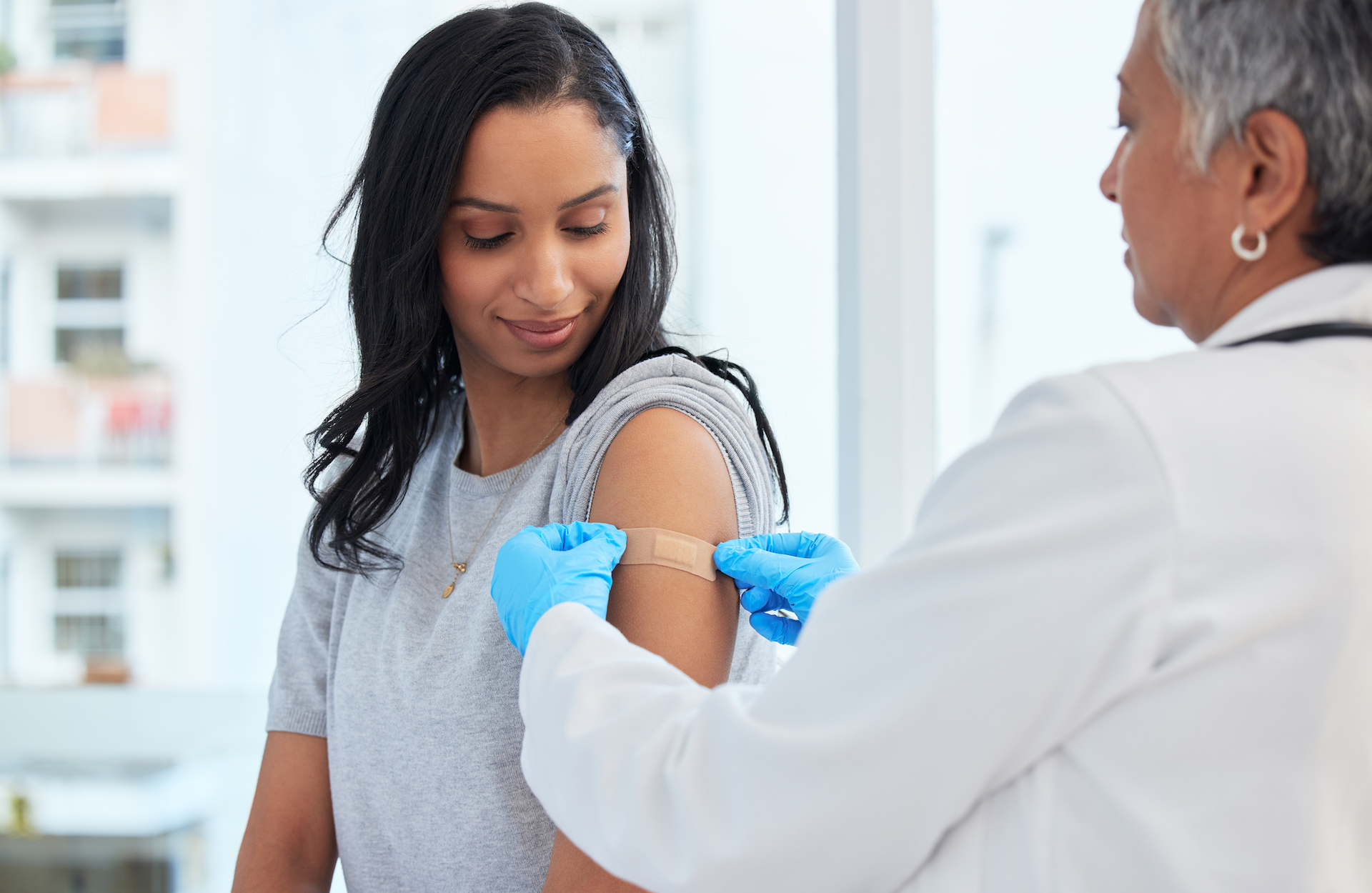 Doctor placing a bandage on a patient's arm after vaccination