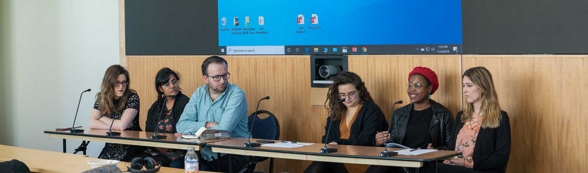 Six students seated at a table, with one speaking