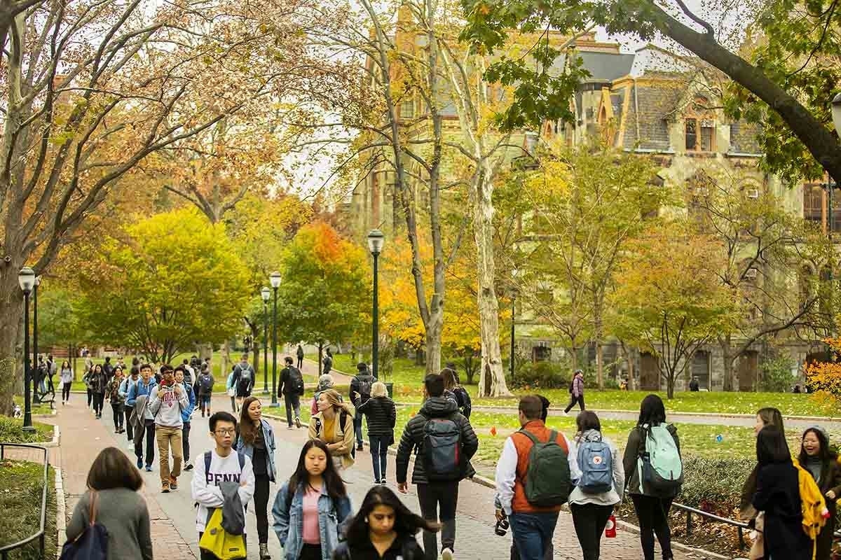 Students walking on Locust Walk, with academic buildings in the background and fall trees