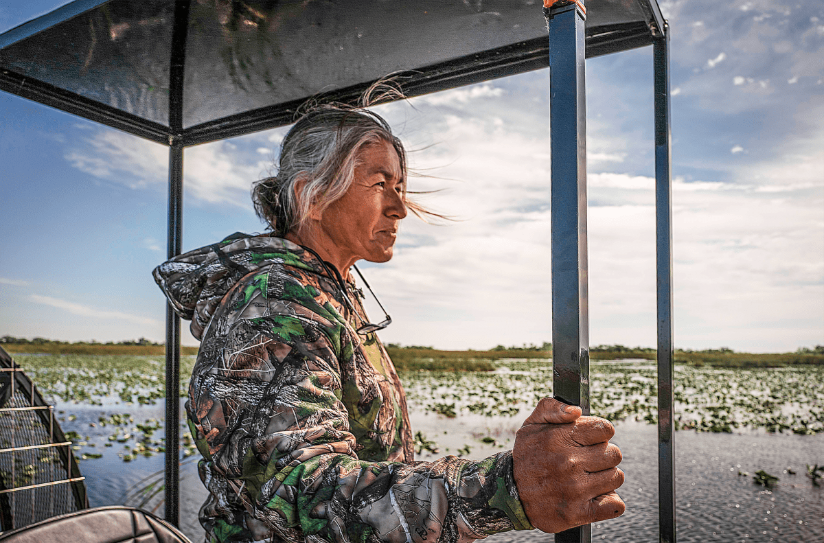 Woman in a boat looking out over a marsh