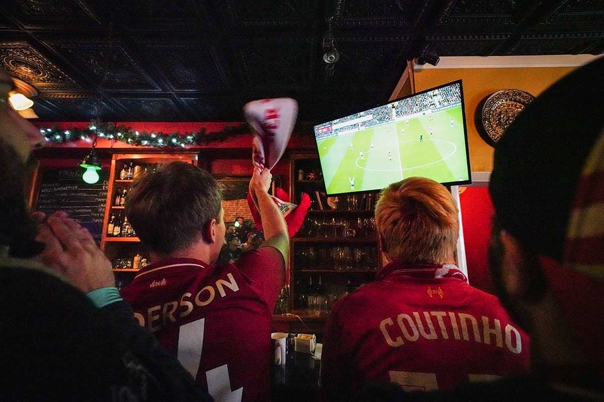 People in soccer jerseys watching soccer on TV and cheering