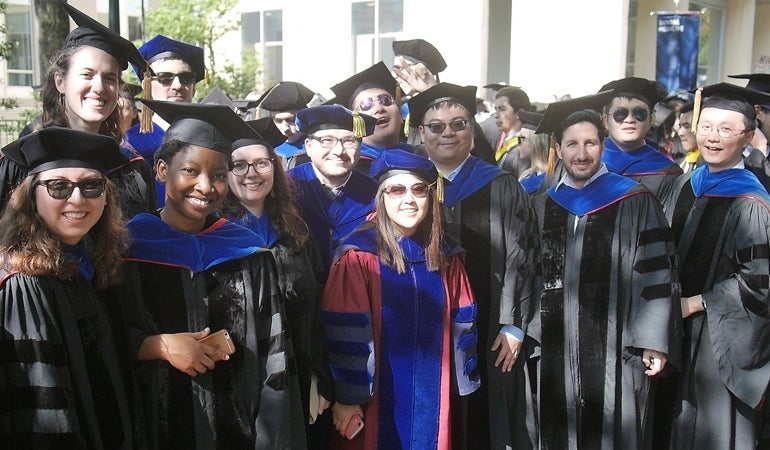 Approximately 15 graduates posing in graduation regalia