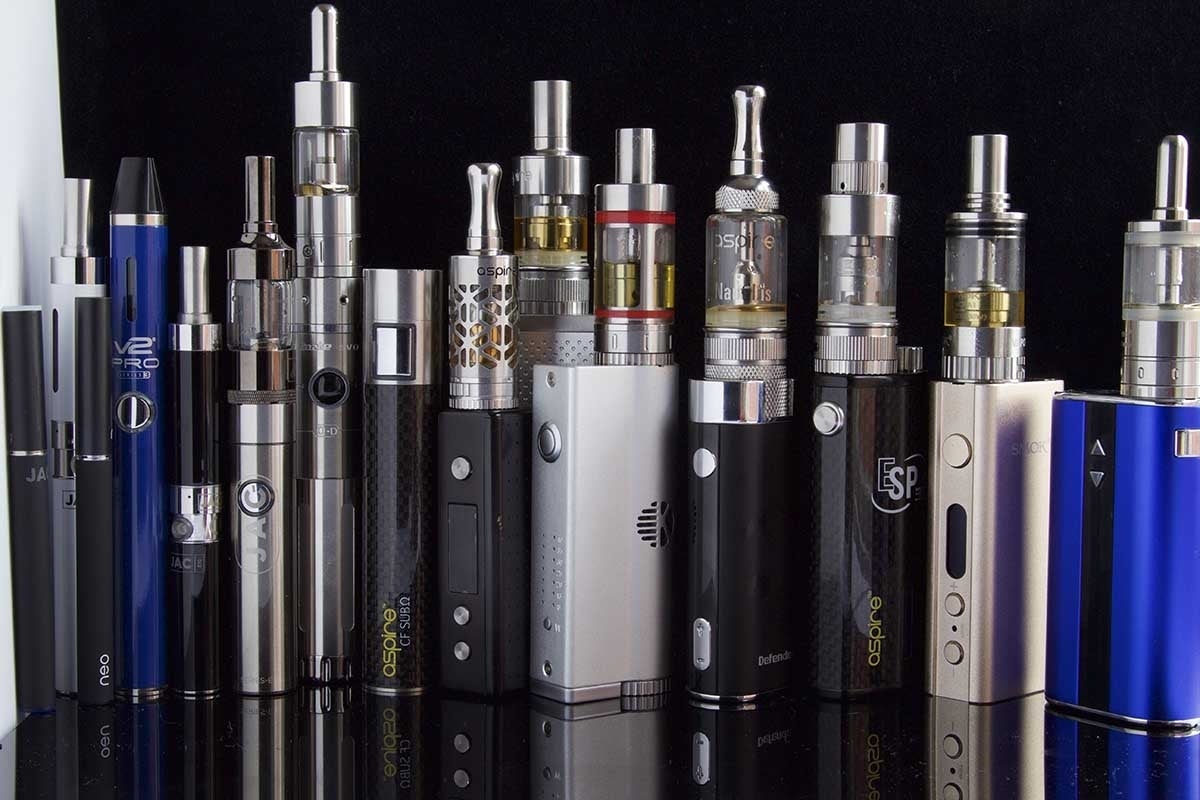 Wide variety of blue, white and black e-cigarettes with silver tops on a black table