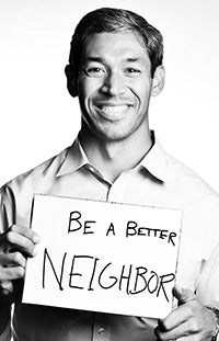 Black and white chest-up photo of Ron Nirenberg smiling. He holds a sign that says 'Be a Better Neighbour'.