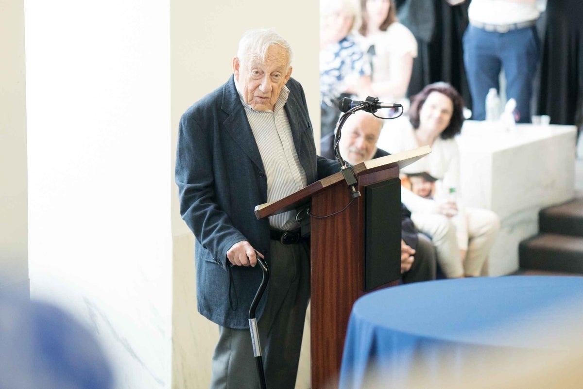 Elihu Katz speaking at a podium with an audience in the background