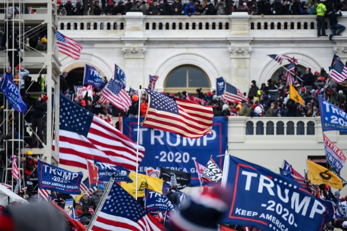 Dozens of Trump 2020 and American flags wave as people overtake the Capitol on Jan. 6, 2021.