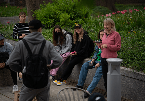 Diana Mutz speaking outdoors with students sitting around her