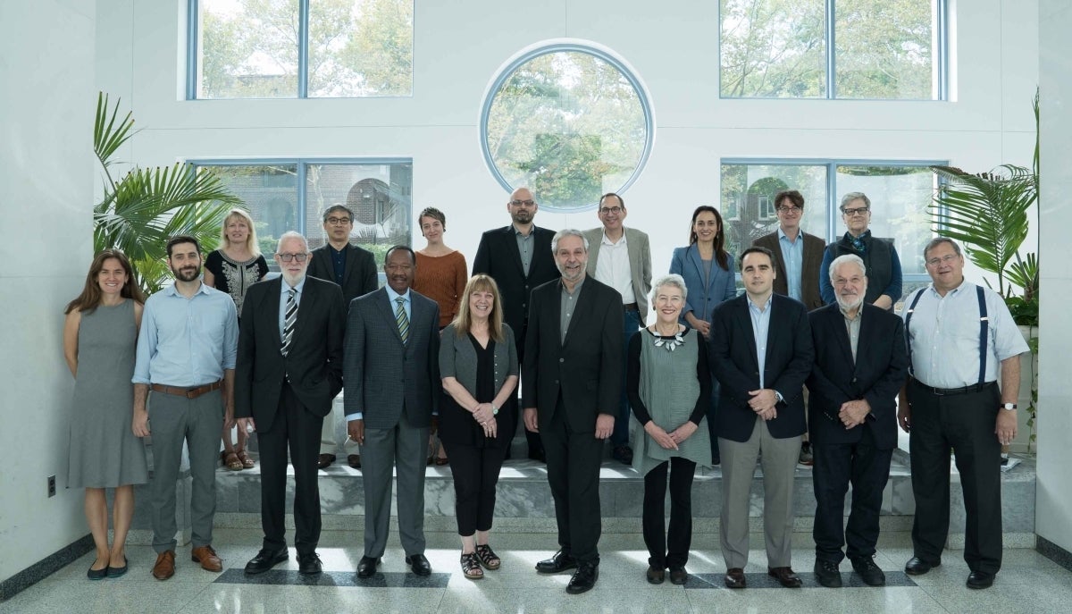 Many faculty members standing posed for a photo in the Plaza Lobby with the dean in the center