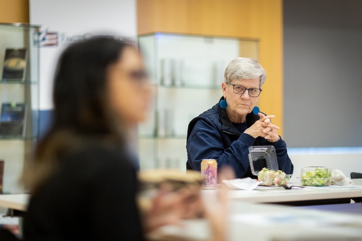  Kathleen Hall Jamieson sits at a table watching a student speak