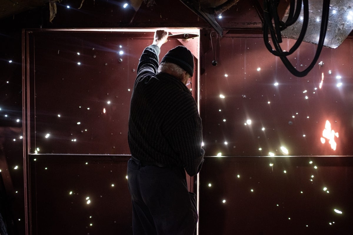 A man opens the door of his garage in Zahaltsi, Borodianka District, Ukraine. April 2022.(Photo: Olexiy Furman)