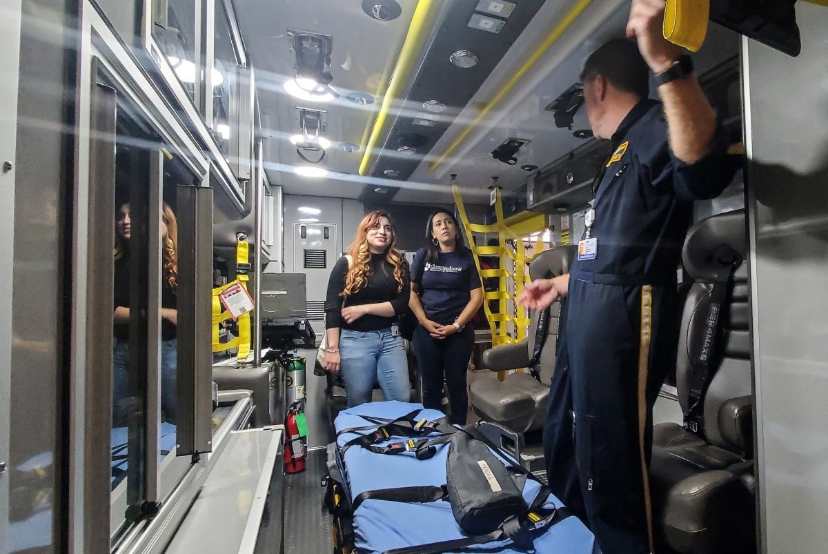 Jocelin Monge and Esperanza Martinez stand in an ambulance talking to an EMT at Children's Hospital of Philadelphia