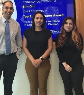 Murali Balaji, Jocelin Monge, and Esperanza Martinez stand in front of a TV in the lobby of the Annenberg School for Communication