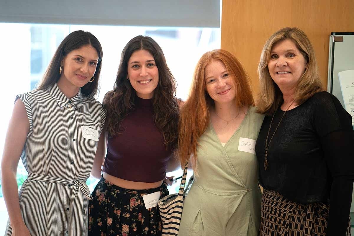 Four women posing for a photo while standing