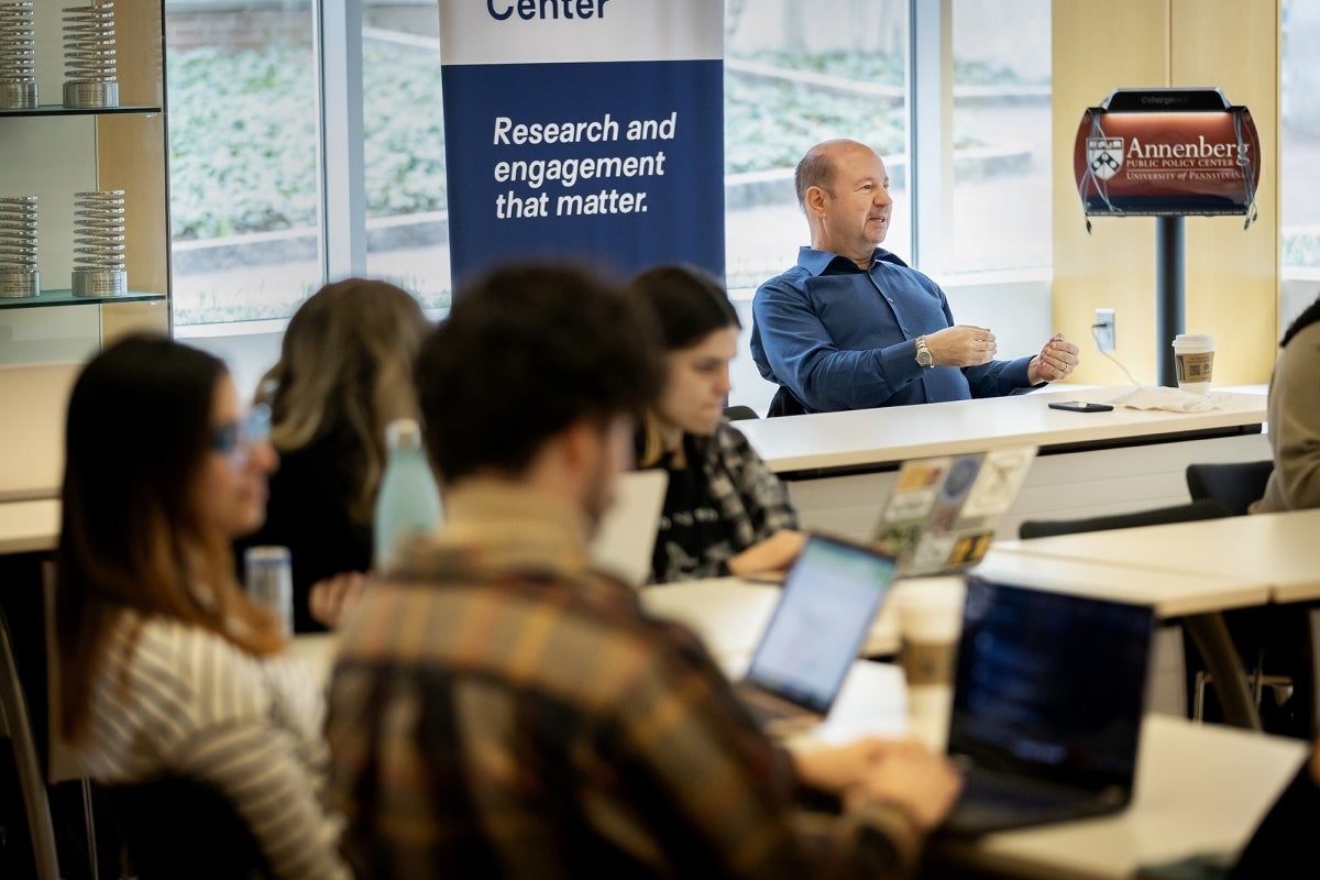 Michael Mann seated while teaching in a classroom.