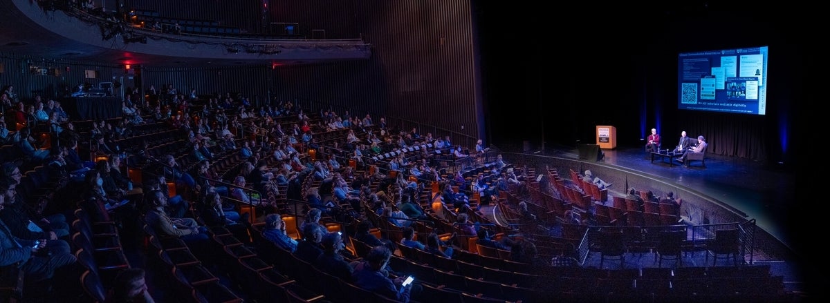 Attendees watch Jamieson, Mann, and Weiss during the opening night plenary discussion.