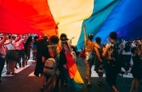 A photo of people under an LGBTQ flag at a Pride parade