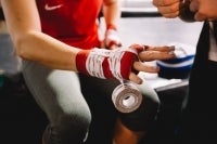 Image depicts a person having their hand wrapped. Presumably the hand of a boxer getting ready to fight