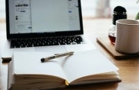 Open laptop and open notebook with pen on desk