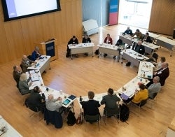 APPC agora circle 700 x 550.jpg Circle of people sitting around desks in a large open room, viewed from high above