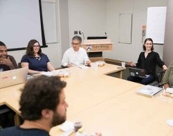 MARC meeting.jpg Five people seated around a classroom table smiling and talking