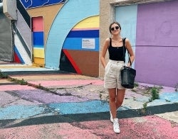 Anna Callahan 700 x 550.jpg Anna Callahan standing in front of a building painted in bright colorblocks. The street is also painted.