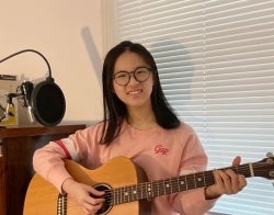 Cindy Huang 700 x 550.jpg Cindy Huang holding an acoustic guitar and sitting in front of a microphone